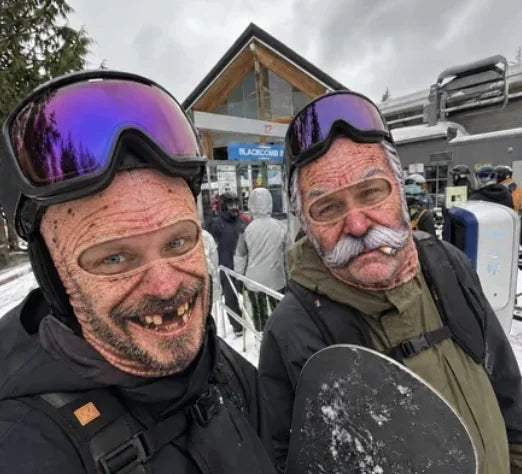 Two skiers wearing AgeSwap realistic elderly face ski masks